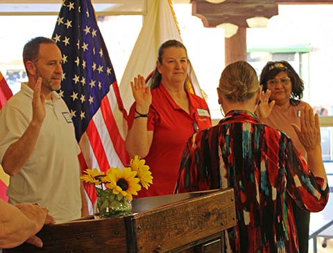 Berry Larson, (facing away) the Winslow Chamber of Commerce President, inducts Rick Lee (left), Linda Branch (middle) and Tina Scott (right) onto the board for the chamber.
