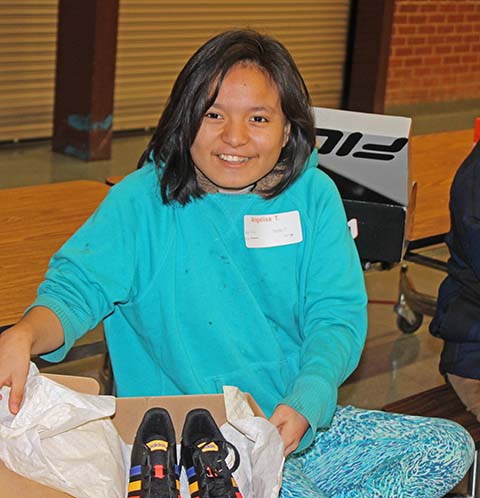 Angelisa T., a student at Winslow Junior High, beams with joy as she tries on her new athletic shoes, a generous gift from Brenda Daly and the organization. Brenda, moved by the desire to honor her son Kevin Haydukovich's memory, has been a dedicated supporter of the charity. Kevin, who had a passion for athletic shoes, is remembered lovingly through this act of kindness. Brenda's initiative to provide new shoes to students in Winslow, has touched the lives of over 585 children.