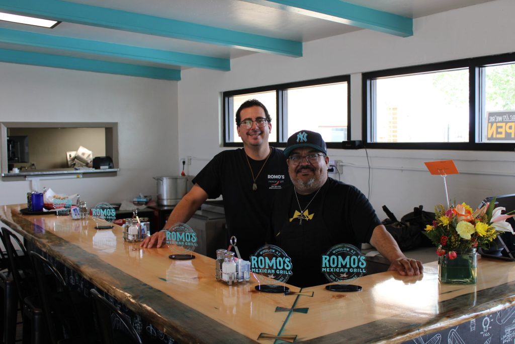 Marcus Espitia (left) and owner Mark Romo stand behind the counter at Romo's Mexican Grill, Winslow's latest culinary addition, now permanently located on the Winslow Airport tarmac. Visitors can savor their meal while enjoying the view of planes taking off and landing.