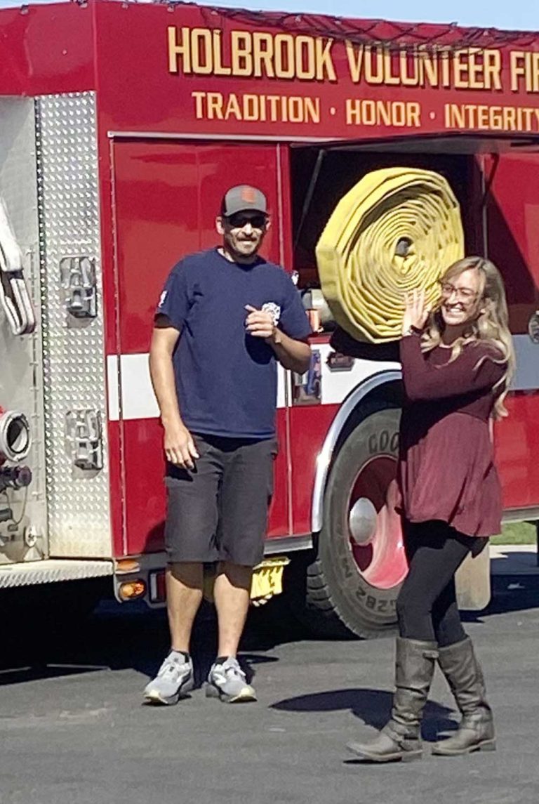 Kindergarten teacher Meagan Newton-Pender (right) races to knock down water bottles with the fire hose as firefighter Michael Young (left) looks on.