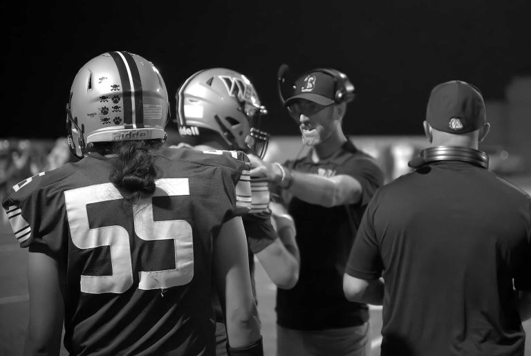 Head Coach Jordan Payne gives his Bulldog quarterback encouragement during a difficult game. Let's all of us give positive comments to the players and cheer them on for the next home game against Chinle on Oct. 10.