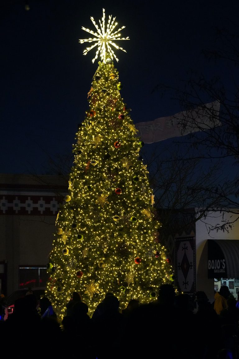 A crowd forms around the City of Winslow’s Christmas Tree during the third annual lighting ceremony last Friday at the Route 66 Plaza in historic downtown. The lights in the park were turned off so everyone can full take in the beauty of the tradition.