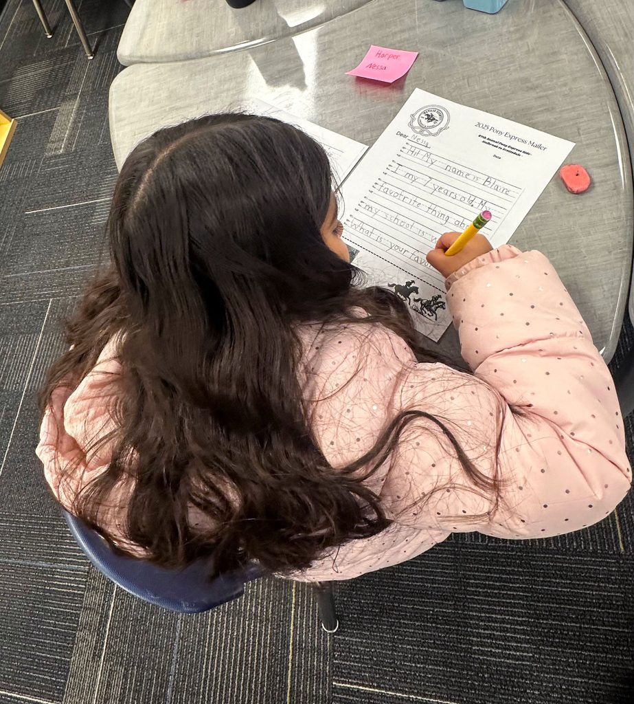 First grader Blaire Barela writes her Pony Express letter for a pen pal.