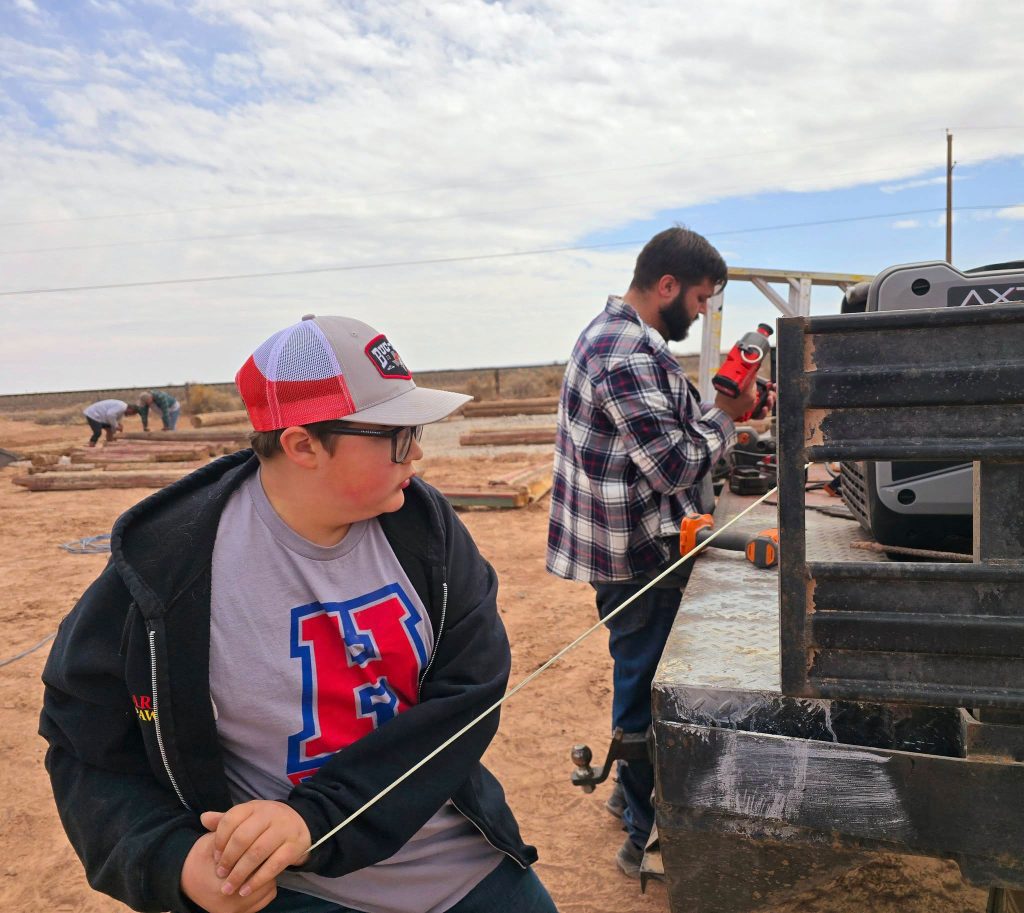 For the Jaquez family, preserving cultural icons along Route 66 is a way of life. The Jack Rabbit Trading Post was purchased in 1967 by Cindy Jaquez’ father, Glenn Blansett and is now owned by Cindy and her husband Tony. Here their son PJ Jaquez (right) and his son Stratton (left) work together along with family and volunteers to reconstruct Ella’s Frontier Trading Post (seen in the background) next to the trading post owned by their family.