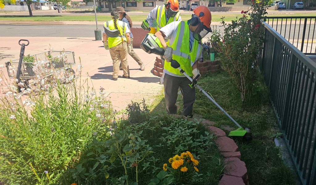 YCC youth spent the day beautifying the Holbrook Public Library by clearing out weeds and planting flowers. Chase Sherman (left) and Emery Yazzie (right) took on the task of cutting down the dense weeds and grass that grew along the library.
