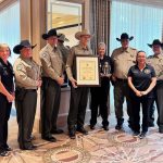 Navajo County Sheriff David Clouse (center) is surrounded by staff as he proudly displays the office’s certificate of accreditation as well as a plaque received.