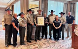 Navajo County Sheriff David Clouse (center) is surrounded by staff as he proudly displays the office’s certificate of accreditation as well as a plaque received.