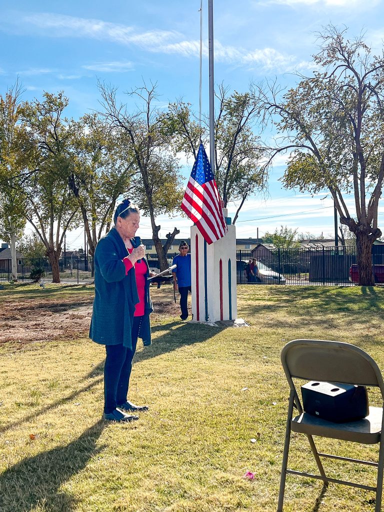 Bert Cole speaks during Monday’s Veterans Memorial service at Desert View Cemetery as Rudy Montoya raises the flag.