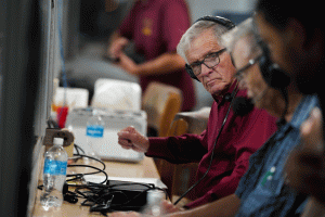 Loy Engelhardt calls a Winslow Bulldogs football game from the press box at Emil Nasser Stadium. For nearly six decades, Engelhardt's voice carried Winslow athletics into living rooms and kitchens across Navajo County.
