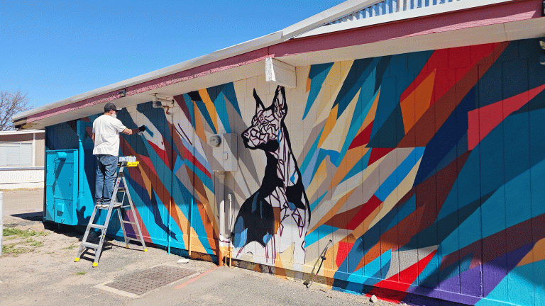 Muralist Wes Abarca creating another vibrant work of public art, this time transforming the exterior walls of the Mr. G’s building along U.S. Route 66 in Joseph City. Abarca has been steadily adding color to the region’s Route 66 corridor, completing murals on three buildings in Holbrook and two more in Winslow. The newest piece features the beloved pet of Mr. G’s owners, Bryan and Julie Fields as well as a Route 66 shield for a great photo opportunity. Abarca says he hopes his work encourages other artists in the region to share their creativity and leave their own mark on their communities. To see more of Abarca’s artwork, follow him on Facebook at www.facebook.com/wes7svn or on Instagram @wes7svn.