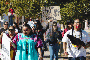 A group of volunteers with Turtle Island Women Warriors demonstrate outside the Arizona Capitol in November 2024 to raise awareness about Indigenous community members displaced by the state's massive Medicaid fraud scheme.