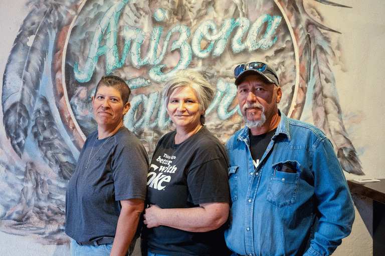 Andrea Romo (left) stands with her sister Becki Colon and Aaron Colon in front of the original Arizona Tavern mural inside the nearly finished Gandy Dancer Gallery in downtown Holbrook, a space the family has spent more than a year renovating ahead of its planned opening in May.
