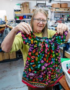 Berry Larson holds up one of the handmade dresses she has sewn through the Winslow Stitchers at Stitchin’ on the Korner in Winslow.