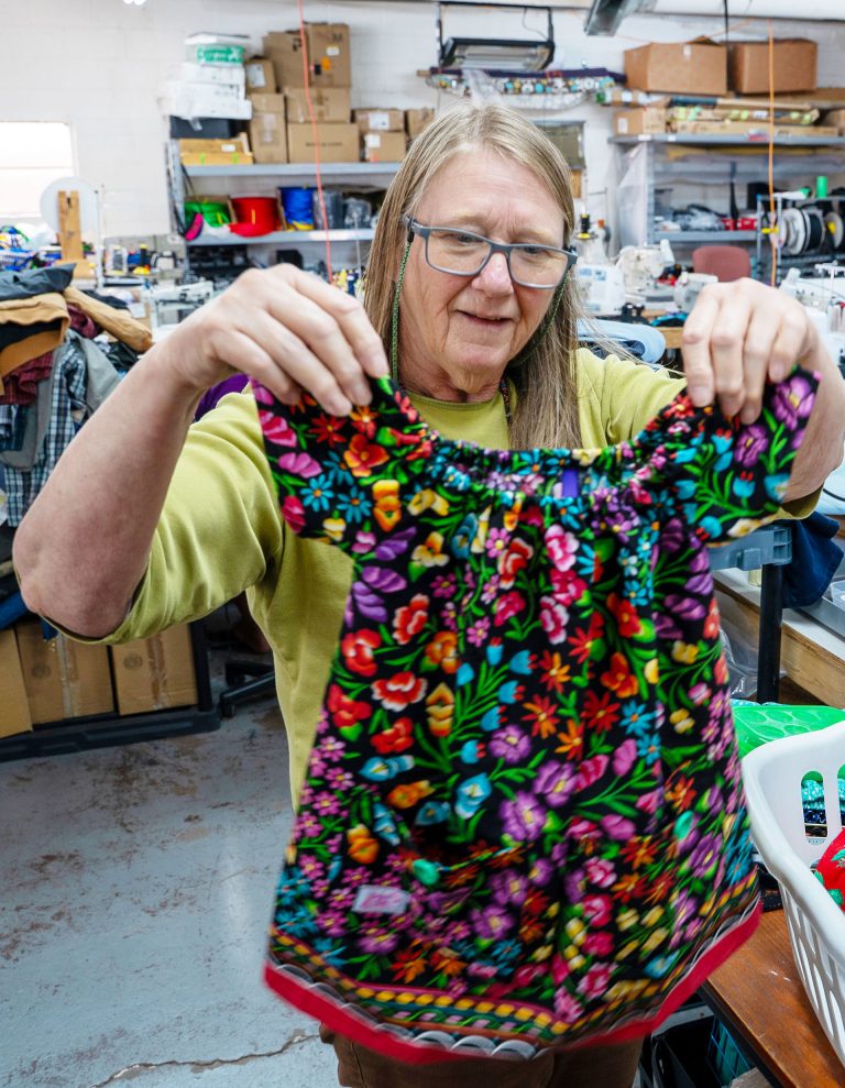 Berry Larson holds up one of the handmade dresses she has sewn through the Winslow Stitchers at Stitchin’ on the Korner in Winslow.