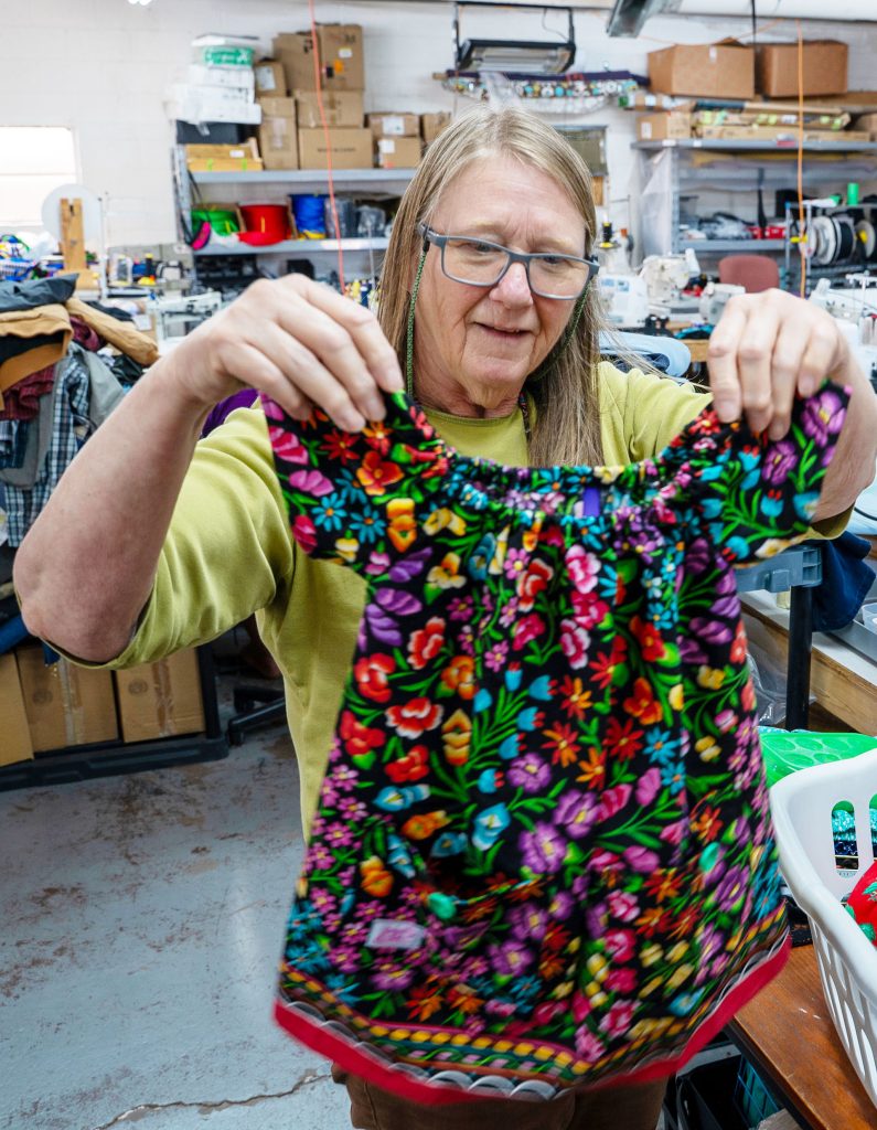Berry Larson holds up one of the handmade dresses she has sewn through the Winslow Stitchers at Stitchin’ on the Korner in Winslow.