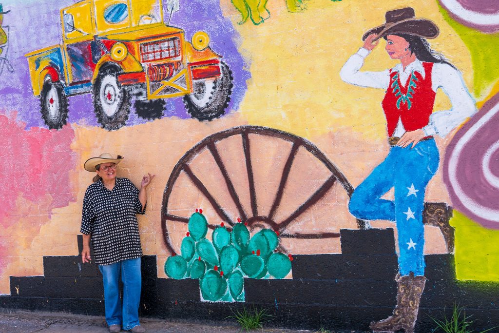 Artist Liz Nichols is pictured with a section of her Holbrook mural, located at the corner of Hopi Drive and Navajo Blvd. which includes symbols and stories connected to her hometown.