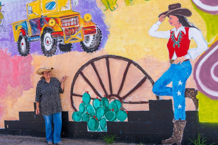 Artist Liz Nichols is pictured with a section of her Holbrook mural, located at the corner of Hopi Drive and Navajo Blvd. which includes symbols and stories connected to her hometown.