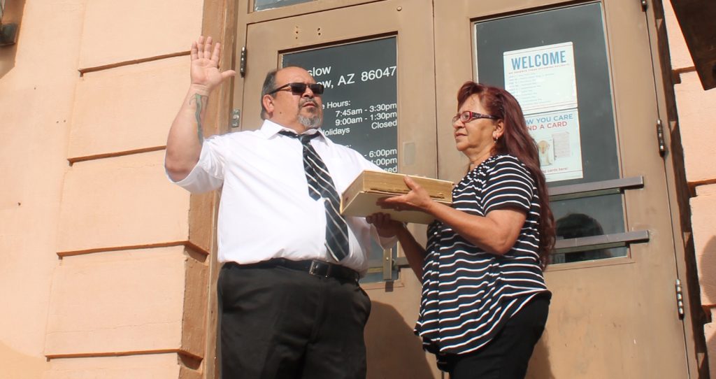 Photo by Linda KorArthur Gonzales puts his hand to a Bible held by his wife Martha as Marla Lacy, head of post office operations in Phoenix, swears him in as Winslow’s new postmaster.