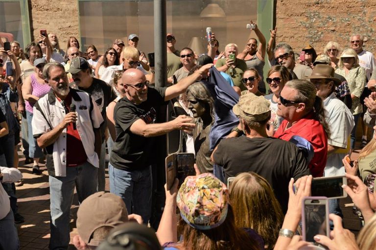 Photo by Richard LarsonWinslow celebrated the unveiling of a new bronze statue in the likeness of Glenn Frey at the Standin’ on the Corner Park Sept. 24. The statue was revealed before a crowd of about two hundred people by KSLX radio host Mark Devine (center). KSLX covered most of the cost of making of the statue, but Tom McCauley (to the left of Devine) was instrumental in adding this tribute of the Eagle’s founder and co-writer of the town’s theme song, Take It Easy.