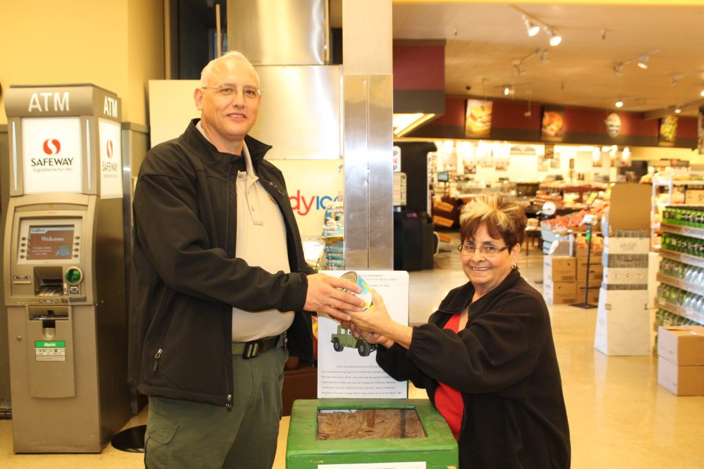 Photo by Linda Kor - Holbrook resident Anna Murray (right) does her part to help those in need during the holiday season by contributing to the Catholic Charities food pantry. Police Chief Mark Jackson (left) set out collection boxes in various businesses throughout the city, including this one at Safeway.