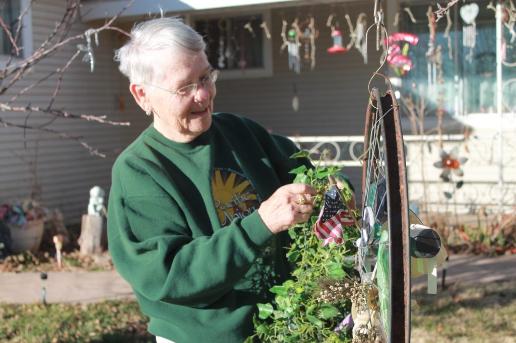 Photo by Chanae NielsonMerilyn Brewer takes pride in the distinctive yard art at her Snowflake home. Her son John Beecroft, who also makes custom wooden bows, made the bicycle spoke creations that decorate the yard. Here she adds more ivy to one of them, as the high winds sometimes necessitate replacing the items inside.