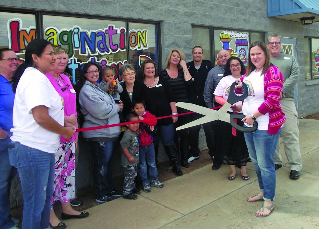 Photo by L. Parsons The Winslow Chamber of Commerce recently welcomed Imagination Station to the business community. Owner Melissa Nelson (right) wielded the scissors at the ribbon cutting. The new daycare facility offers before and after school care, all day care, preschool and an infant room. Imagination Station is located at 1313 E. Third Street in Winslow. Also present were (left to right) Tammy Curley, Michelle Pennington, Berry Larson, Lori Romero, Kathy Patton, Darcey McKee, Cathy Galvan, Michael Mendoza, Frank Guzman, Alicia Aguilar and Chamber CEO Bob Hall.