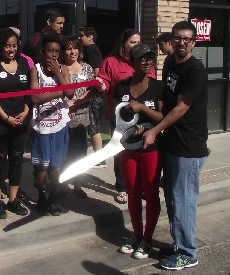 Photo by L.ParsonsOwners Jonnie Powell Cabebe (left) and Mike Cabebe (right) prepare to cut the ribbon in front of their new nutrition center, Rise n' Grind.