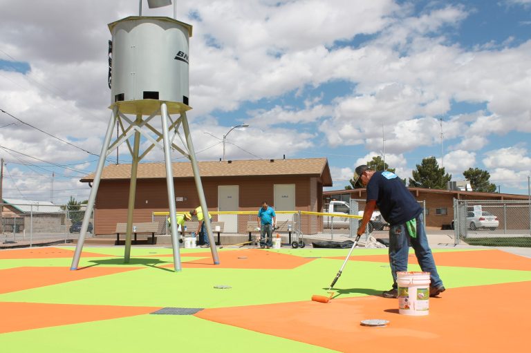 Photo by Linda KorThe City of Holbrook is getting its recreational facilities ready for some summer fun, including a new paint job and sealant for the splash pad. Facilities and Maintenance Head Tim Kelley (front) puts on a second coat of bright orange paint to go with the lime green, a combination of what he called “kid-friendly colors.” Also lending a hand on the project are (left to right) City Manager Randy Sullivan, city employee Michael Young and Mike Stockley of Commercial Pool Repair. The splash pad will be open by the end of this week.
