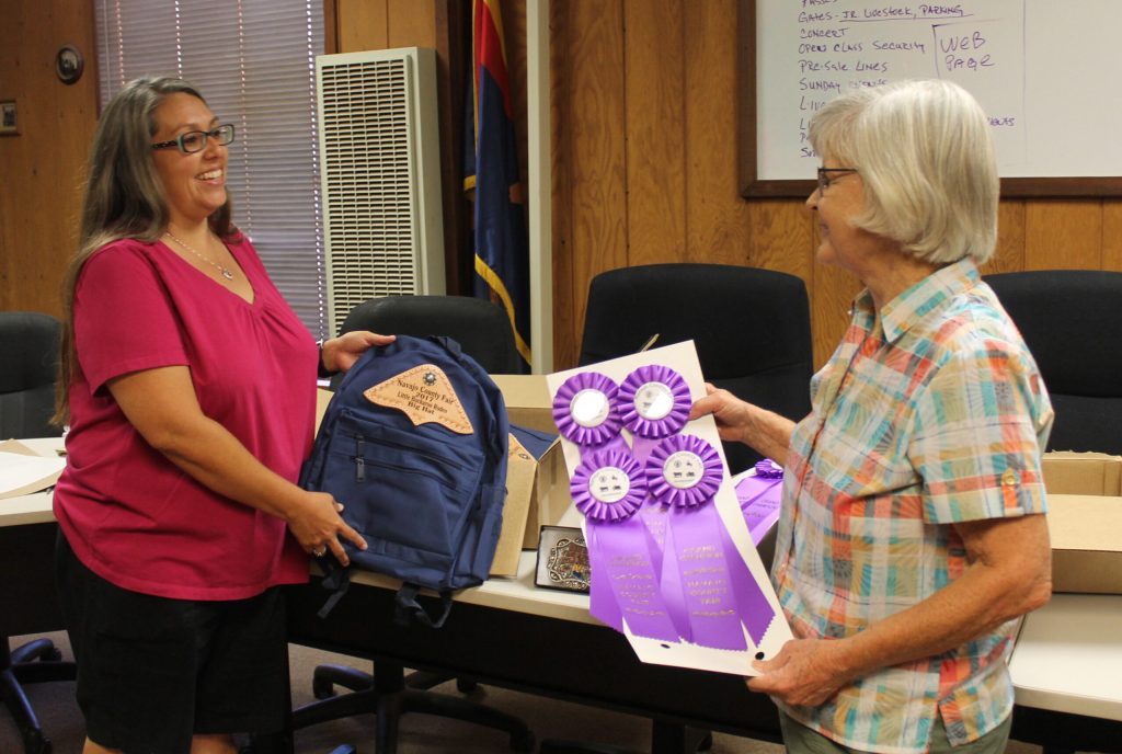 Photo by Linda KorEmployees and volunteers are hard at work at the Navajo County Fairgrounds in Holbrook in preparation for the upcoming Navajo County Fair. Event Coordinator Jme Baloo (left) and fair board member Ginnie Arthur (right) sort through backpacks, buckles and ribbons that will be presented to the winners of the various events that will be taking place.
