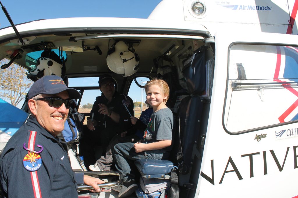 Photo by Linda KorTaylor Elementary School students enjoyed a recent day at Freeman Park as emergency responders took time out of their busy schedules to allow the youngsters inside a fire truck, an ambulance and a helicopter. Ziein Hescock (right) sits in a Native Air helicopter while flight nurse Dan Weber (left) and flight paramedic Tanna Stalter (middle) show him how everything works.