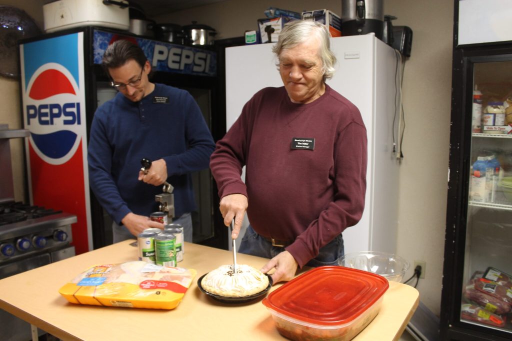 Photo by Linda KorThe Bread of Life Mission in Holbrook is one of a number of organizations in the area that provides for those less fortunate this holiday season. In addition to providing a hot Christmas meal, the mission strives to provide small gifts for each of its guests. The mission is in need of food, and small items such as spiral notebooks, socks and hygiene items. They also welcome any leftover foods from parties, or other events. Here Mission Manager Ron Ellsworth (left) and Kitchen Manager Tim Miller prepare for an upcoming meal for the 39 people staying at the mission.