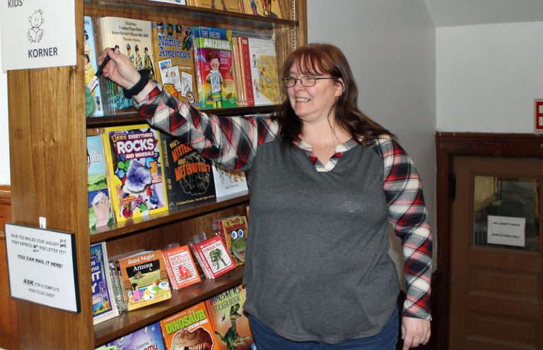 Photo by Toni GibbonsDesk Clerk Dawn Sawyer takes a moment to dust one of several shelves of children’s books that are located in the bookshop at the historic Navajo County Courthouse.