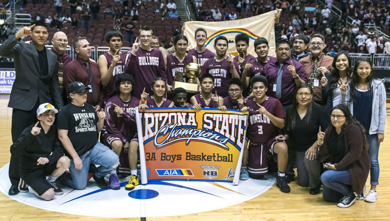 Photo by Richard LarsonThe Winslow Bulldogs won 2018 3A state championship with a 79-63 win over the Blue Ridge Yellowjackets on Feb. 26. Pictured are (front row, left to right) Coach Corum’s son Zane Corum, team statistician Tysen Leonard, players De Angelo Lewis, Theron Olney, Yoann Djassa, Darius James, Torrin Yazzie, Skyler Barlow, Coach Stephanie Nelson, Manager Cheyne Lowry, (back row) Coach Stevin Nelson, Coach Jim MacLean, Head Coach Scott Corum, Zachary Wagner, Elias Stewart, Ricardo Villanueva Jr., Jalen Lyons, Issac Benale, Tyrell Young, Dakota Spencer, Coach Venton Nelson, Coach Gary Sanderlin, Manager Shanden Joe and Manager Miranda Neboyia. Navajo Nation President Russell Begaye and Vice President Jonathan Nez were present and are pictured here holding the Navajo Nation flag. Navajo Nation President Russell Begaye and Vice President Jonathan Nez are pictured behind the players holding up the flag of the Navajo Nation.