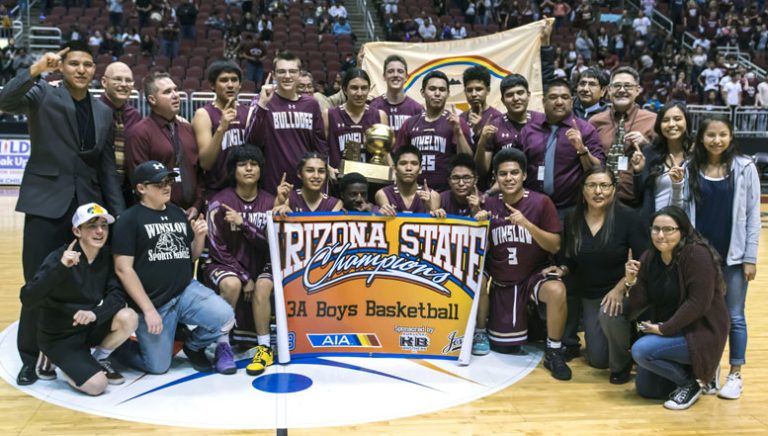 Photo by Richard LarsonThe Winslow Bulldogs won 2018 3A state championship with a 79-63 win over the Blue Ridge Yellowjackets on Feb. 26. Pictured are (front row, left to right) Coach Corum’s son Zane Corum, team statistician Tysen Leonard, players De Angelo Lewis, Theron Olney, Yoann Djassa, Darius James, Torrin Yazzie, Skyler Barlow, Coach Stephanie Nelson, Manager Cheyne Lowry, (back row) Coach Stevin Nelson, Coach Jim MacLean, Head Coach Scott Corum, Zachary Wagner, Elias Stewart, Ricardo Villanueva Jr., Jalen Lyons, Issac Benale, Tyrell Young, Dakota Spencer, Coach Venton Nelson, Coach Gary Sanderlin, Manager Shanden Joe and Manager Miranda Neboyia. Navajo Nation President Russell Begaye and Vice President Jonathan Nez were present and are pictured here holding the Navajo Nation flag. Navajo Nation President Russell Begaye and Vice President Jonathan Nez are pictured behind the players holding up the flag of the Navajo Nation.