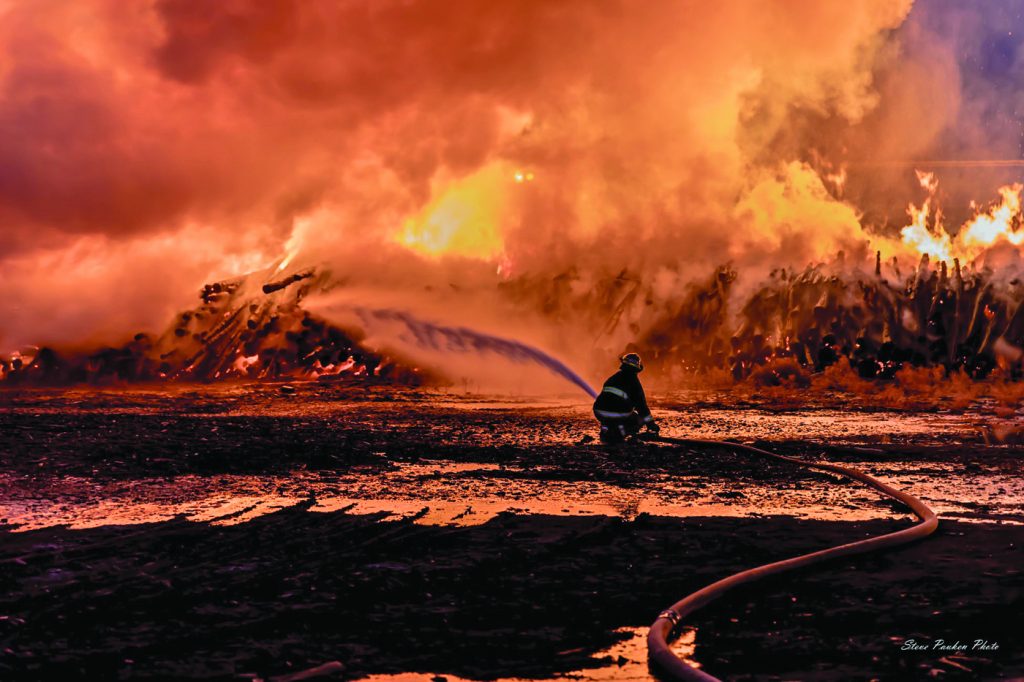 Photo by Steve PaukenA massive fire broke out at a log mill on the west end of Winslow overnight Sunday sending flames hundreds of feet into the air. Crews from the Winslow, Joseph City, Holbrook and Blue Ridge fire departments fought the blaze into the early morning hours of Monday. According to City Manager Steve Pauken, “The log mill fire will be under investigation for awhile. It looks like it consumed about half of the logs on the premises.” The business produces firewood to be bundled and sold at stores nationwide.