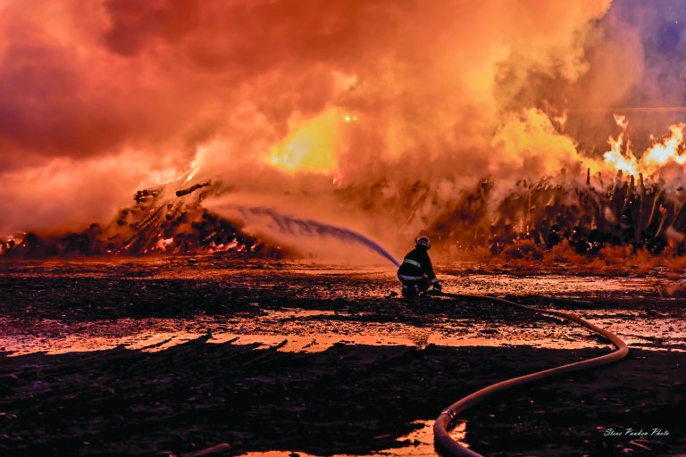Photo by Steve PaukenA massive fire broke out at a log mill on the west end of Winslow overnight Sunday sending flames hundreds of feet into the air. Crews from the Winslow, Joseph City, Holbrook and Blue Ridge fire departments fought the blaze into the early morning hours of Monday. According to City Manager Steve Pauken, “The log mill fire will be under investigation for awhile. It looks like it consumed about half of the logs on the premises.” The business produces firewood to be bundled and sold at stores nationwide.