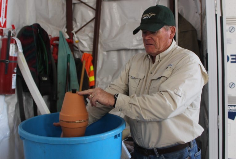Randy Williams with Operation 29:11 demonstrates how to make an Olla pot by gluing two clay pots together and gluing the pot bottom to one to cover the drain hole. A cheap cork fills the other drain hole and allows for water to be put in periodically.