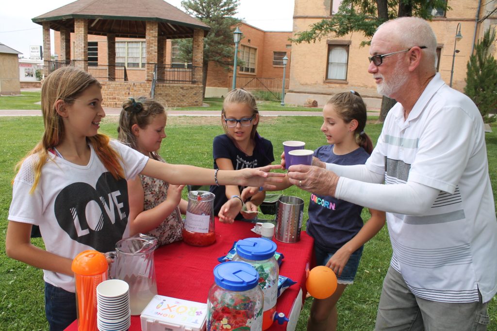 Photo by Linda KorChloe Pettice, Avery Farley, Karoline Belknap and Marina Rossi (pictured left to right) work to help fund a new roof for the Navajo County Historic Courthouse at 25 cents a cup with a lemonade stand they started on the courthouse lawn. Kim Belknap (right) gets a cool drink to help support the endeavor. A new roof for the courthouse is estimated to cost $175,000 but the girls said that they believe it’s a worthwhile endeavor to help preserve history.