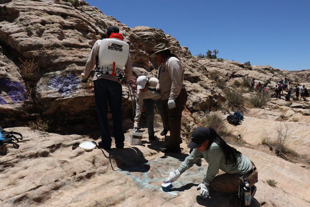 Photo by Henry PalmerUsing all natural graffiti remover and a scrub brush, the Native Conservation Corps Hopi crew tackled the vulgar graffiti on the rocks at Clear Creek camp last month. Hopi crew leader Hali Lomayesva (foreground) is hard at work scrubbing on the rocks.
