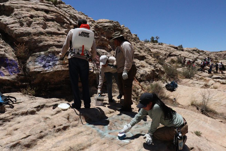 Photo by Henry PalmerUsing all natural graffiti remover and a scrub brush, the Native Conservation Corps Hopi crew tackled the vulgar graffiti on the rocks at Clear Creek camp last month. Hopi crew leader Hali Lomayesva (foreground) is hard at work scrubbing on the rocks.