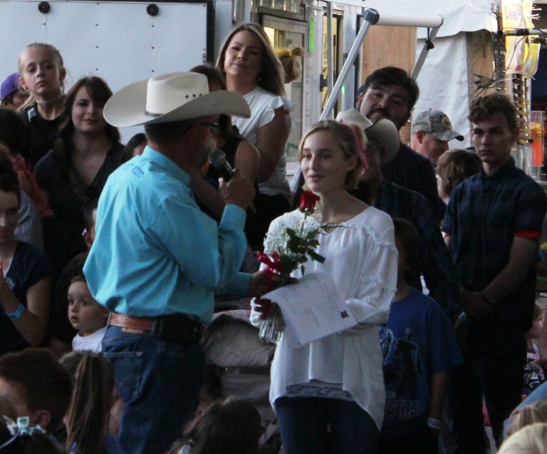 Photo by Toni GibbonsAbby Carlisle (right) receives a rose from J.R. DeSpain (left) in appreciation for her performance of the “Star Spangled Banner” during the opening ceremony at the Navajo County Fair on Sept. 12.