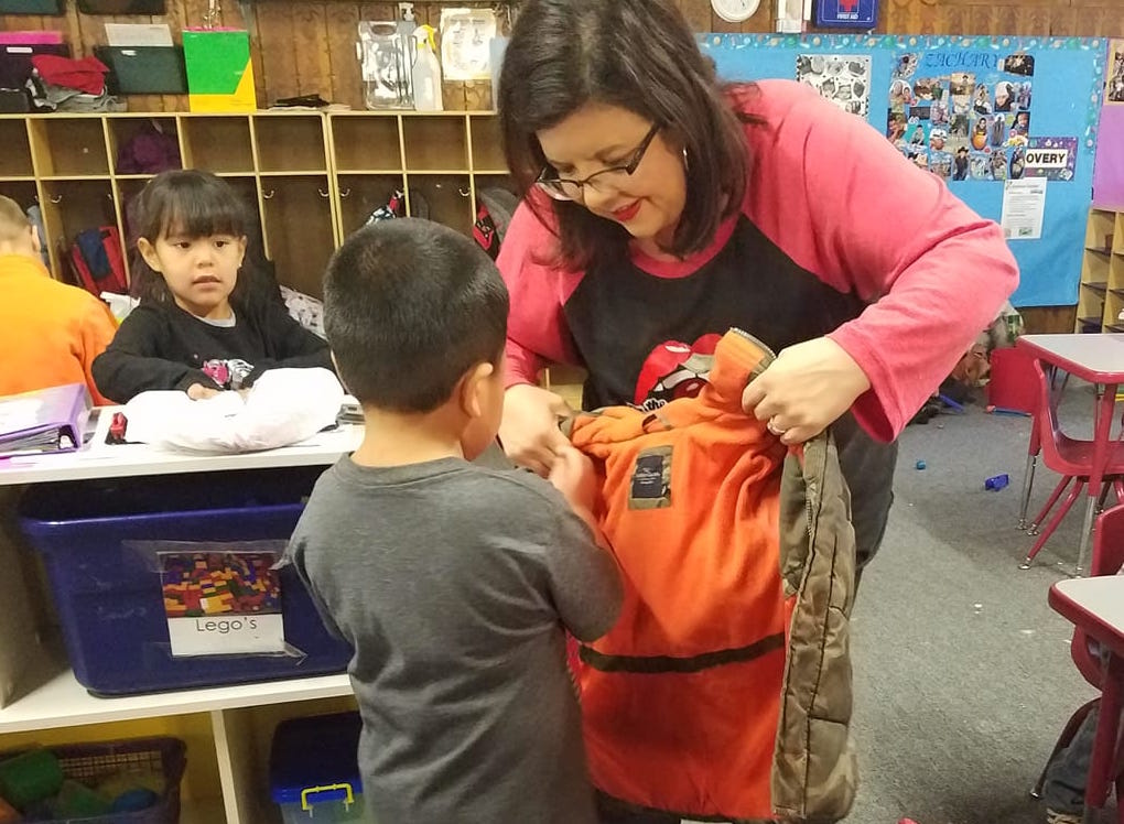 Photo by L. ParsonsOn Nov. 13, area charity group The Cherry Bombs delivered over 120 jackets, coats, winter hats and gloves, and other clothing to the Winslow Head Start. The group began collecting the winter wear in October and relied heavily on the communities of Winslow and Holbrook to fill the needs. Here, Cherry Bomb Jillian Stotts helps a young child on with his new coat as student Ava Francis (left) looks on.