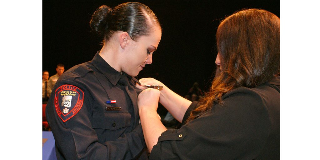 Photo by Everett RobinsonHolbrook Police Officer Heidi Hunsaker (left) was one of 14 new officers sworn in Dec. 14, after completing Northland Pioneer College's 19-week Northeastern Arizona Law Enforcement Academy. Hunsaker, who was raised in Joseph City, had her badge pinned on her uniform by her sister Chalet Loos (right).