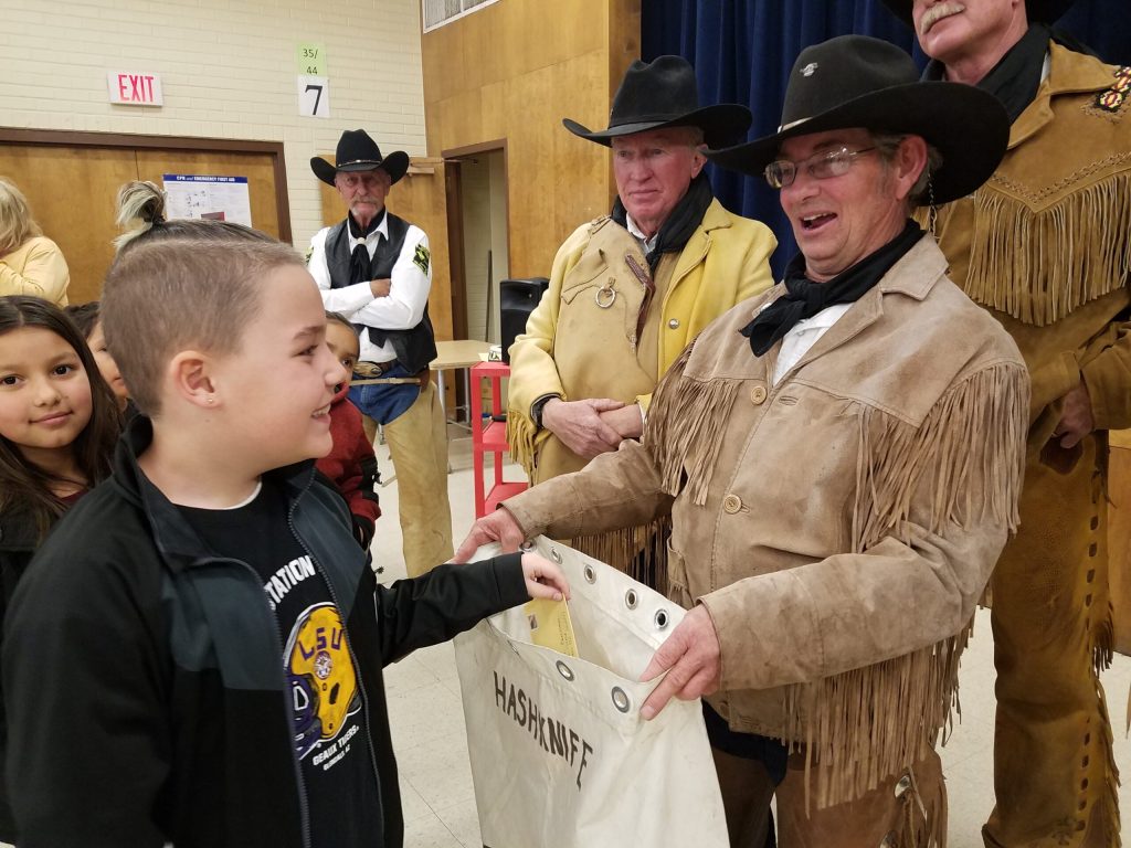 Photo by L. ParsonsFirst grader Maxx Lewis (left) places his letter in the bag of a Hashknife rider last week in preparation for the annual Hashknife Pony Express Ride that left Holbrook this morning (Feb. 6). The Posse presented a question and answer period at Jefferson Elementary School before collecting letters to be delivered via Pony Express.