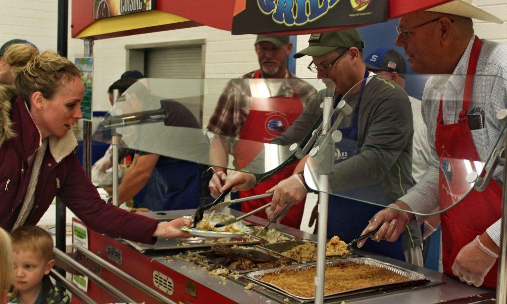 Photo by Toni GibbonsApril Brimhall (left) of Snowflake, helps her young son, Brant Brimhall, get his plate full of biscuits and gravy at the Snowflake Groundhog Breakfast on Feb. 2. Serving the food are (left to right) Taylor Councilman Bill Baldwin, Snowflake Councilman Byron Lewis and Taylor Councilman Shawn Palmer.
