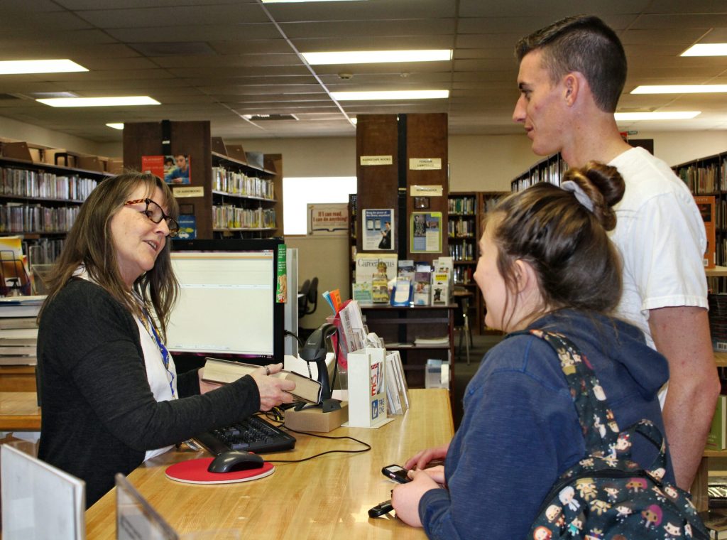 Photo by Toni GibbonsAshlee and Thad Frei (pictured) of Snowflake love to come to the Snowflake Public Library. Ashlee said they are always reading books as they are “important and necessary.” Assisting the Frei’s with their books is Librarian Cathie McDowell (left).