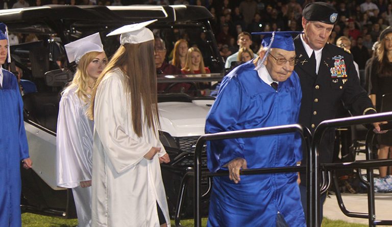 Photo by Toni GibbonsEscorted by his son-in-law Lieutenant Colonel James Gill (far right), Charlie Hall, a 95-year-old World War II veteran, walks to the podium to receive an honorary diploma from Superintendent Hollis Merrell during the Snowflake High School graduation. Walking with Charlie were his grandchildren, (left to right) Tyler Hall, Daiziah McCray and Trinitee Flake.