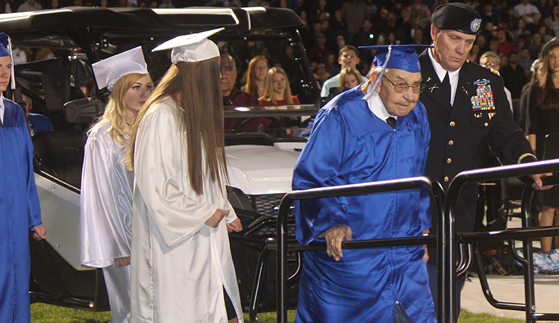 Photo by Toni GibbonsEscorted by his son-in-law Lieutenant Colonel James Gill (far right), Charlie Hall, a 95-year-old World War II veteran, walks to the podium to receive an honorary diploma from Superintendent Hollis Merrell during the Snowflake High School graduation. Walking with Charlie were his grandchildren, (left to right) Tyler Hall, Daiziah McCray and Trinitee Flake.