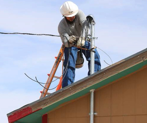 Photo courtesy of Arizona Public ServiceArizona Public Service Lineman Roman Middleton, who grew up in Holbrook, works to connect Elizabeth Begay’s house in Tonalea to the grid during the Light Up Navajo project that connected 233 remote homes on the Navajo Nation to electricity during the six-week pilot project launched in April.