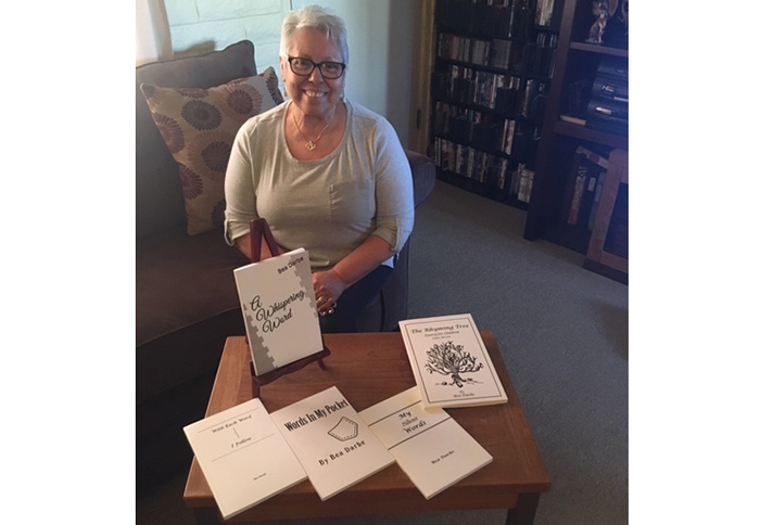 Photo by Linda KorPoet Bea Darbe (pictured) with her collection of books that she’s written over the past four years.